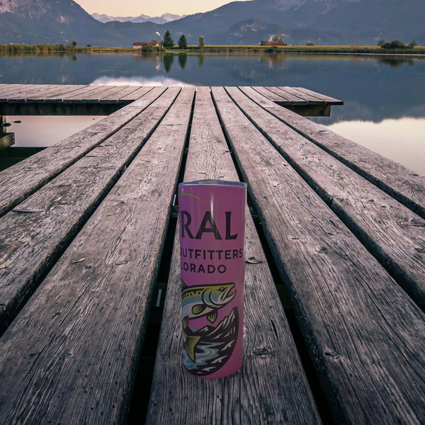 Pink Viral Cast Outfitters tumbler with trout logo on a wooden lake dock at dusk